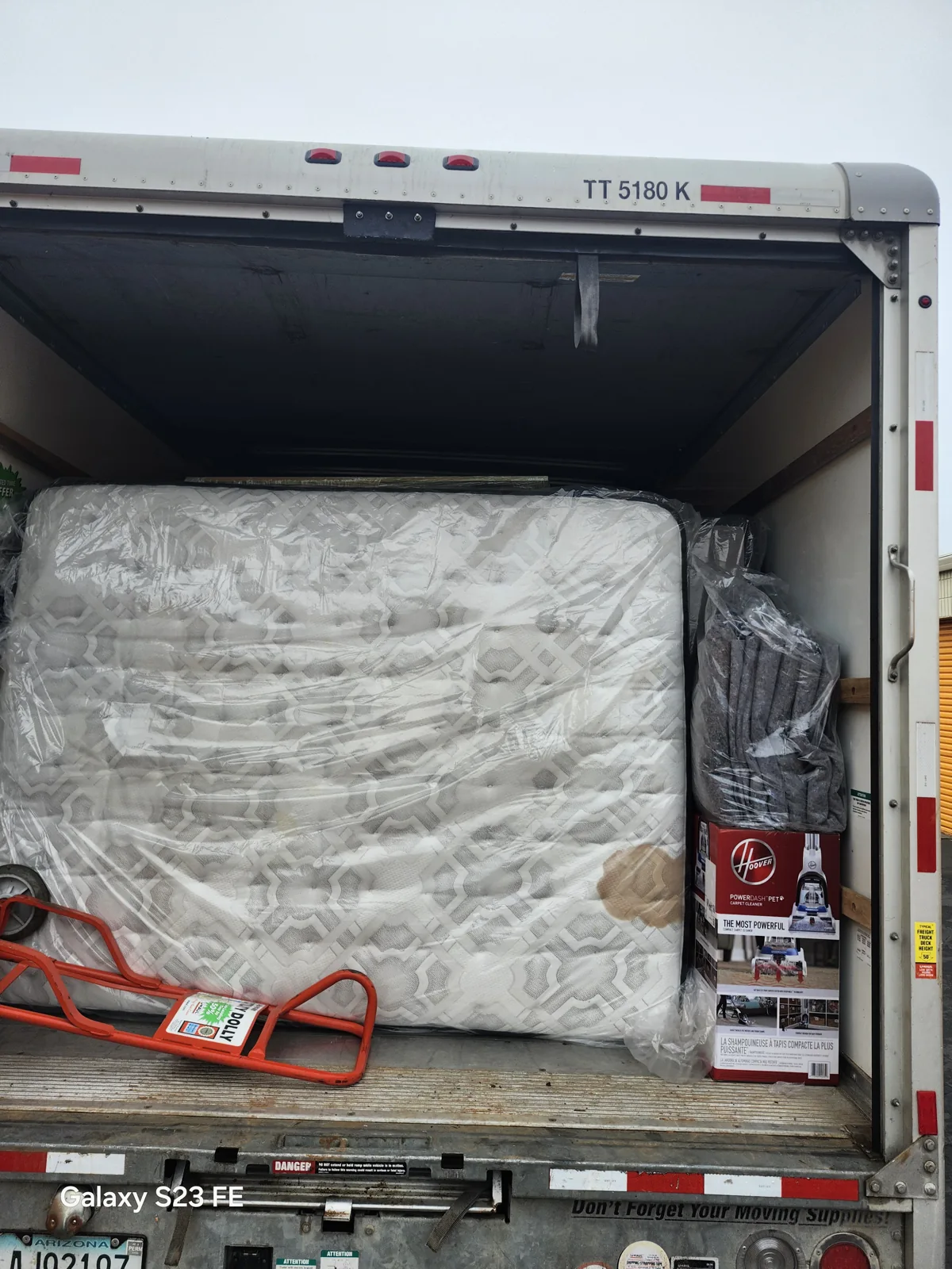 A mattress and household belongings wrapped in protective plastic inside a rental truck during a Rowann job